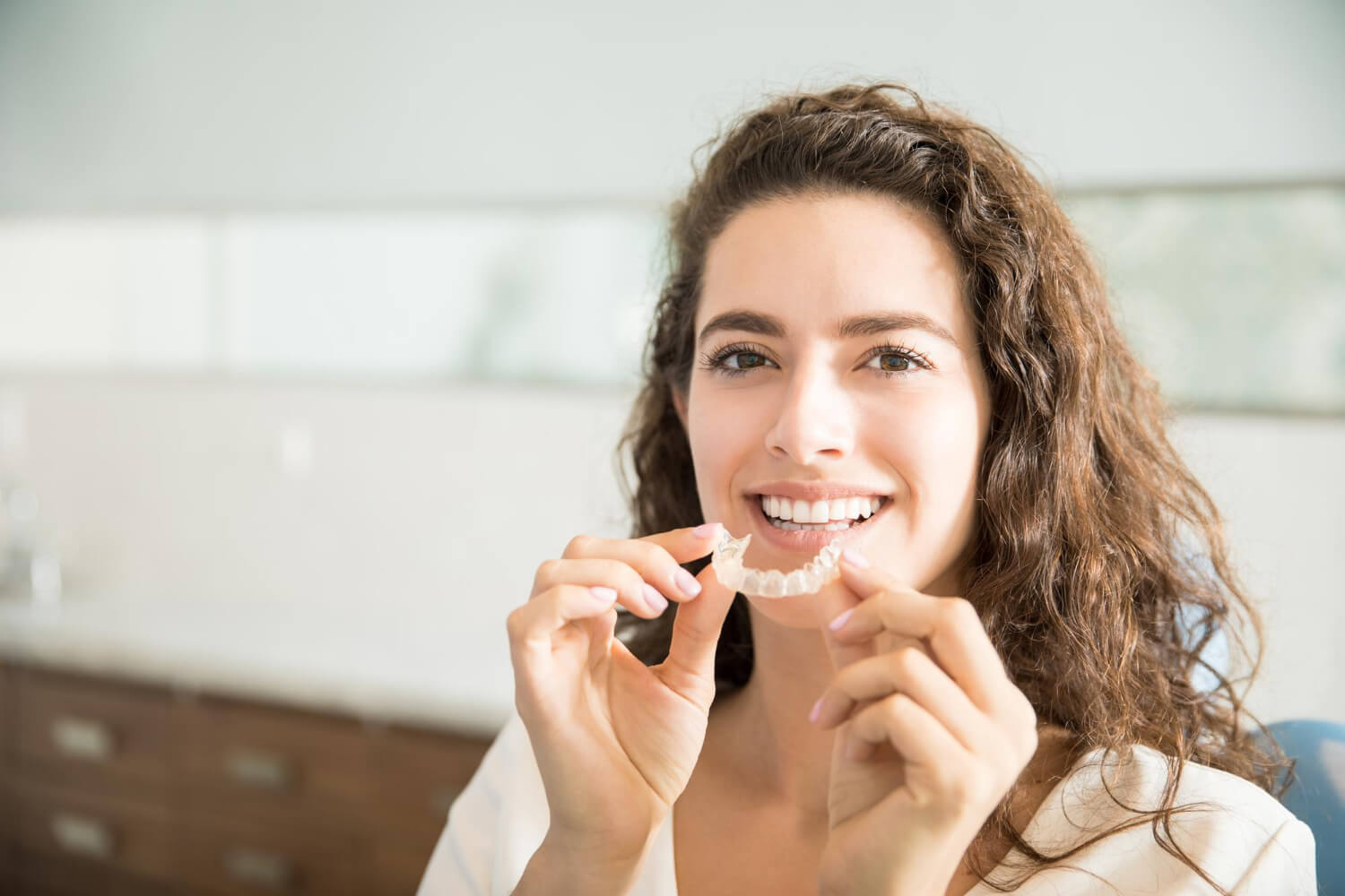 Paciente segurando alinhador invisível Invisalign na Clínica Myai Aricanduva, indicando o tratamento para alinhamento dental.