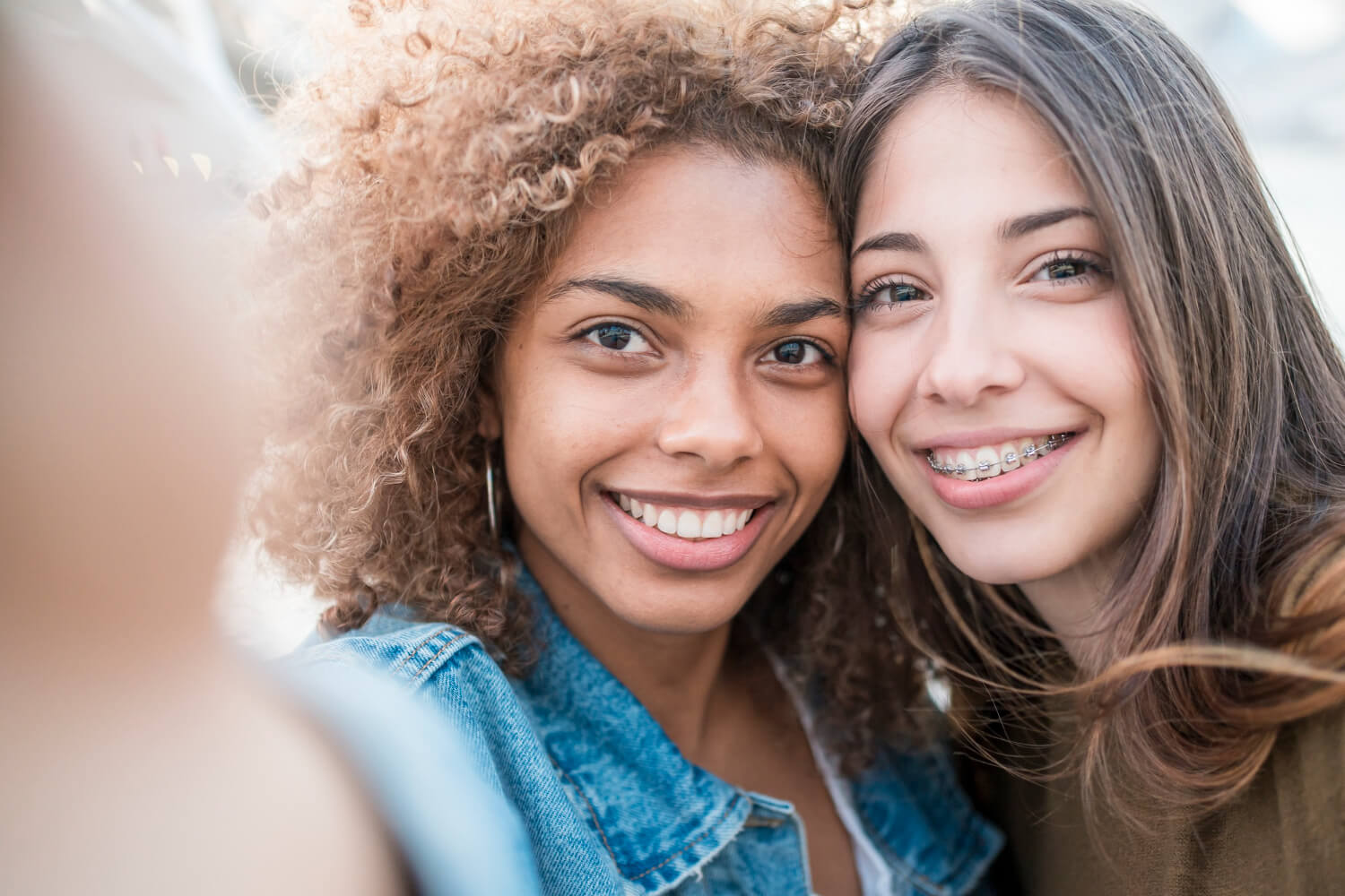 Duas jovens amigas sorrindo radiantes em uma selfie, uma delas usando aparelho. Saiba tudo sobre a contenção ortodôntica em Aricanduva.